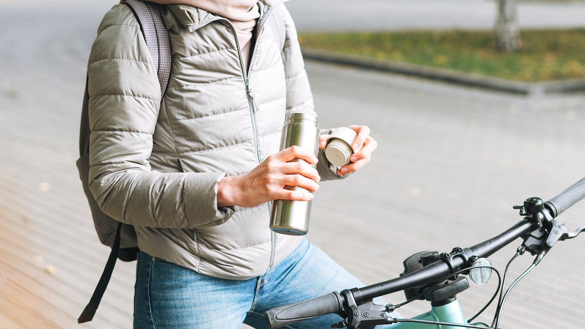Man on a bicycle holding a water tumbler